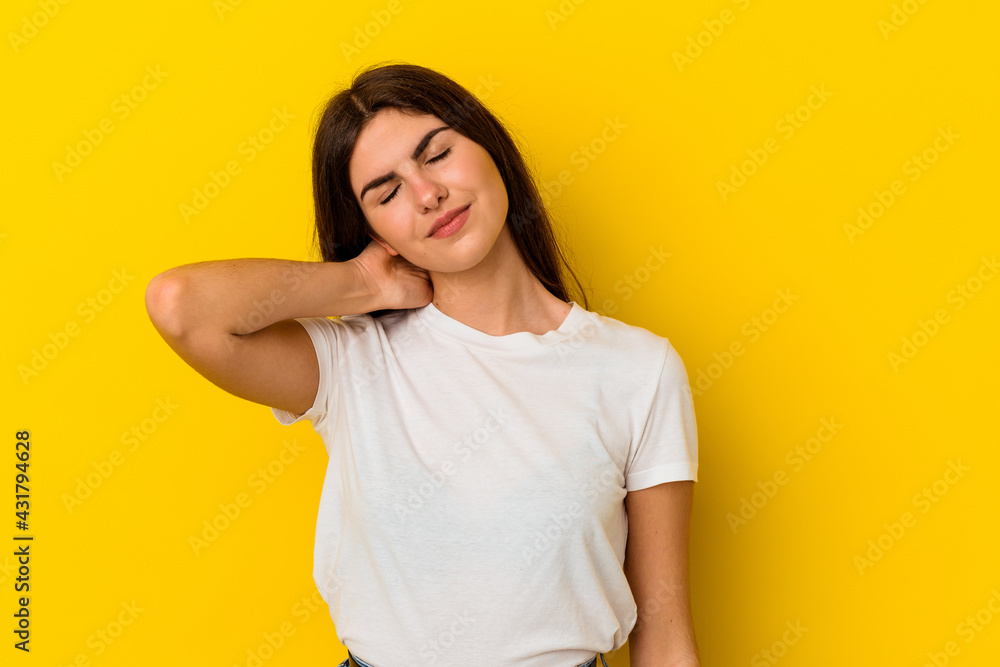 Young caucasian woman isolated on yellow background having a neck pain due to stress, massaging and touching it with hand. Young caucasian woman isolated on yellow background having a neck pain due to stress, massaging and touching it with hand.