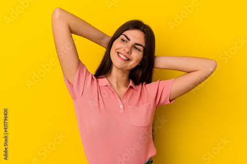 Young caucasian woman isolated on yellow background feeling confident, with hands behind the head.