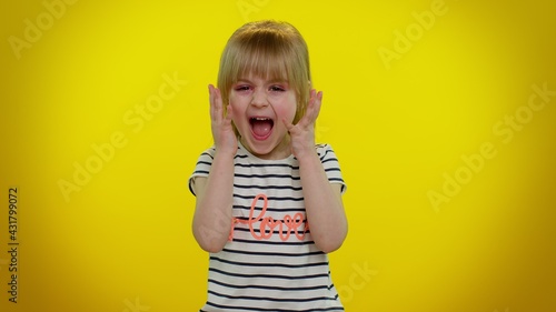 Frustrated unhappy annoyed little blonde teen kid child girl raising hands in displeased expression, quarreling asking reason of conflict, depression. Yellow studio background. Young children emotions