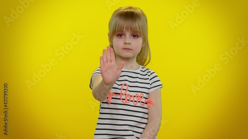 Little child kid girl say no hold palm folded crossed hands in stop gesture, warning of finish, prohibited access, declining communication, body language, danger. Yellow background. Young children
