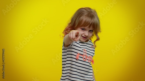 You and me here and right now. We are team. Little child girl looking authoritative, fingers down, demanding immediate serious conversation, giving command. Kid children on yellow studio background