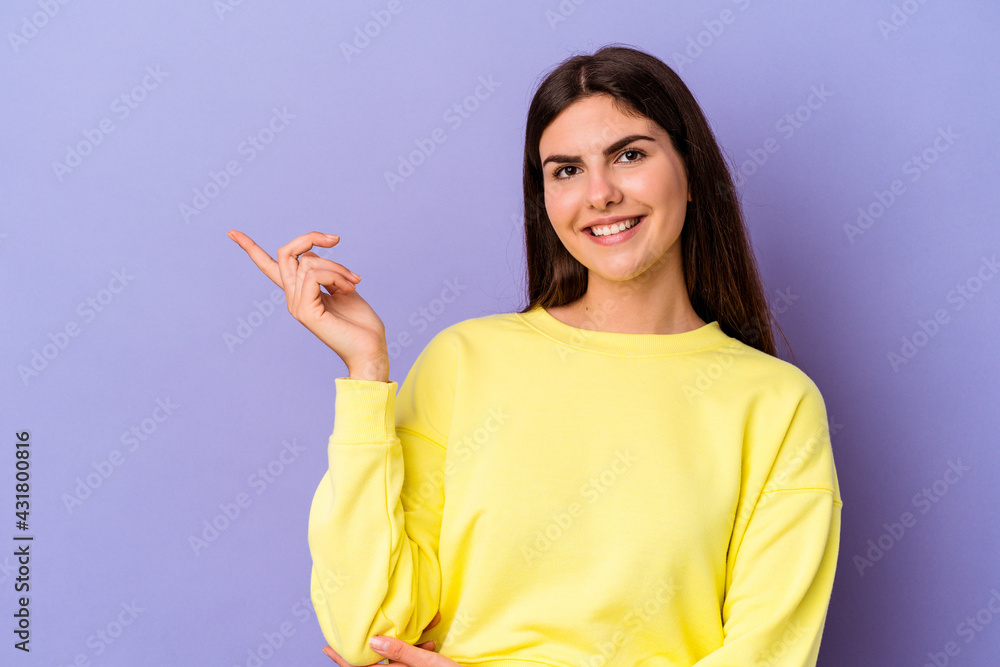 Young caucasian woman isolated on purple background smiling cheerfully pointing with forefinger away. Young caucasian woman isolated on purple background smiling cheerfully pointing with forefinger away.