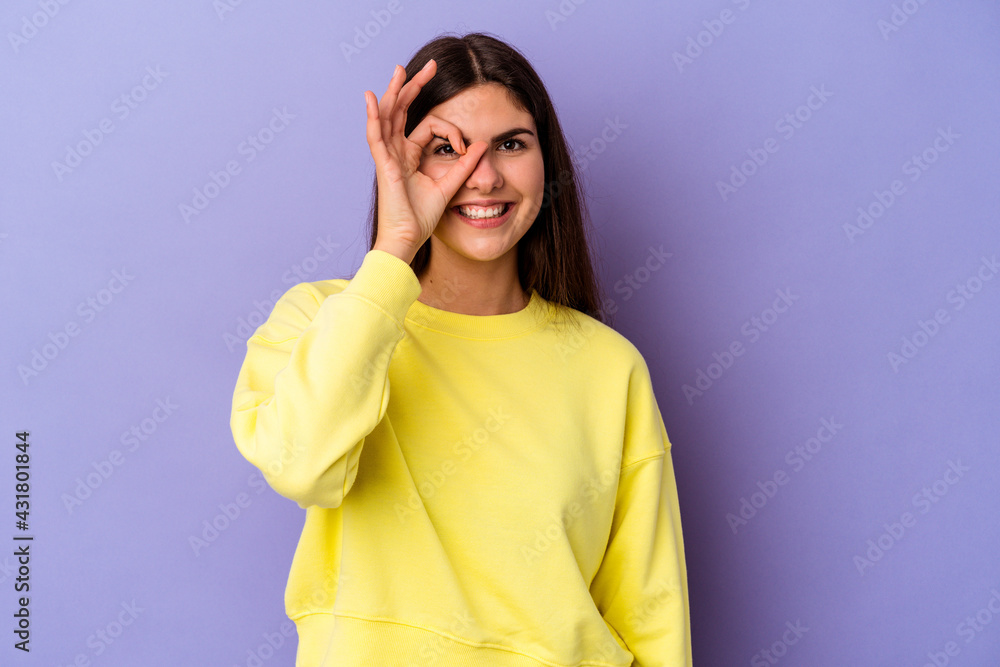 Young caucasian woman isolated on purple background excited keeping ok gesture on eye. Young caucasian woman isolated on purple background excited keeping ok gesture on eye.