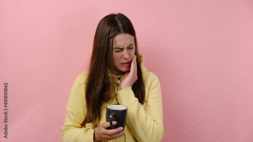 Young brunette female drinking hot or ice-cold beverage and feeling sharp unbearable pain in tooth, periodontal disease, posing isolated on pink studio background wall. Sensitive teeth, damaged enamel Young brunette female drinking hot or ice-cold beverage and feeling sharp unbearable pain in tooth, periodontal disease, posing isolated on pink studio background wall. Sensitive teeth, damaged enamel