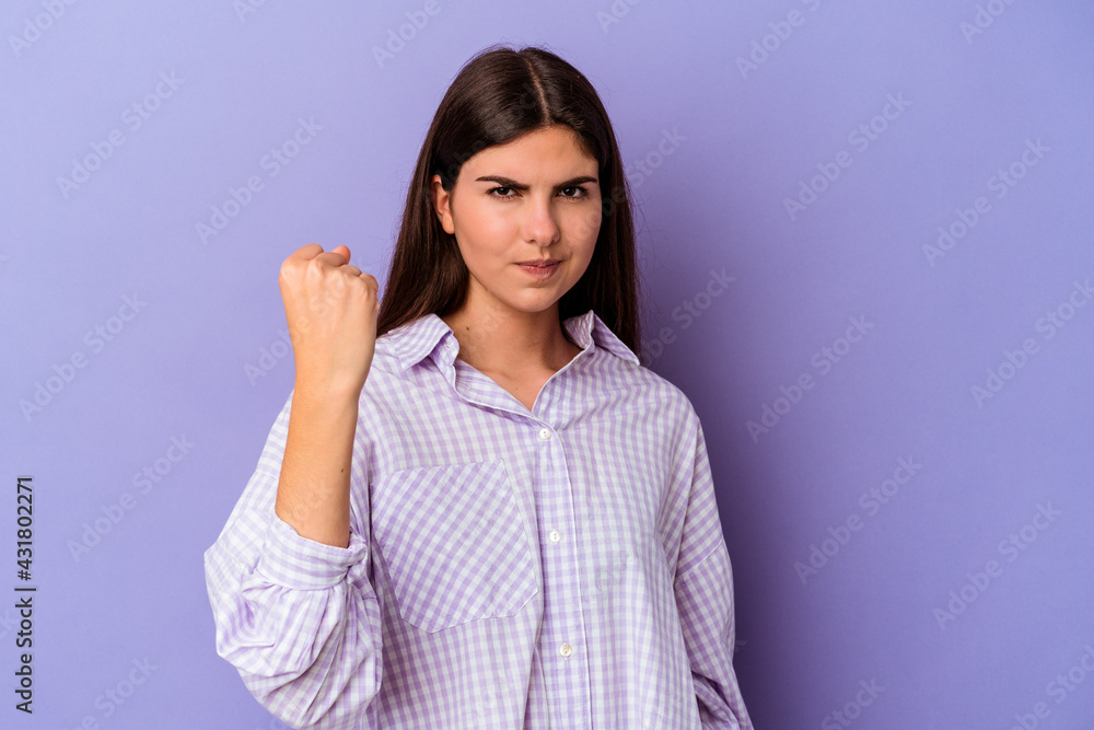 Young caucasian woman isolated on purple background showing fist to camera, aggressive facial expression. Young caucasian woman isolated on purple background showing fist to camera, aggressive facial expression.