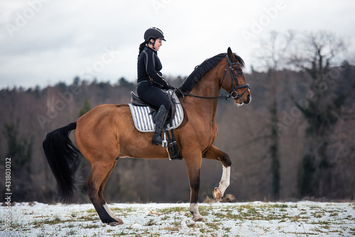 Reiterin mit ihrem Pferd im Schnee in der Schulterparade