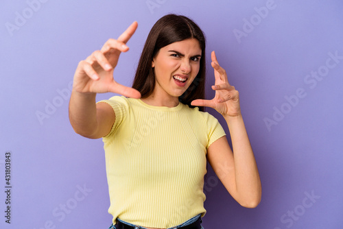 Young caucasian woman isolated on purple background upset screaming with tense hands.