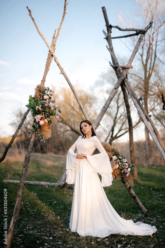 Fototapeta premium A beautiful bride in a light dress poses. Boho style. 