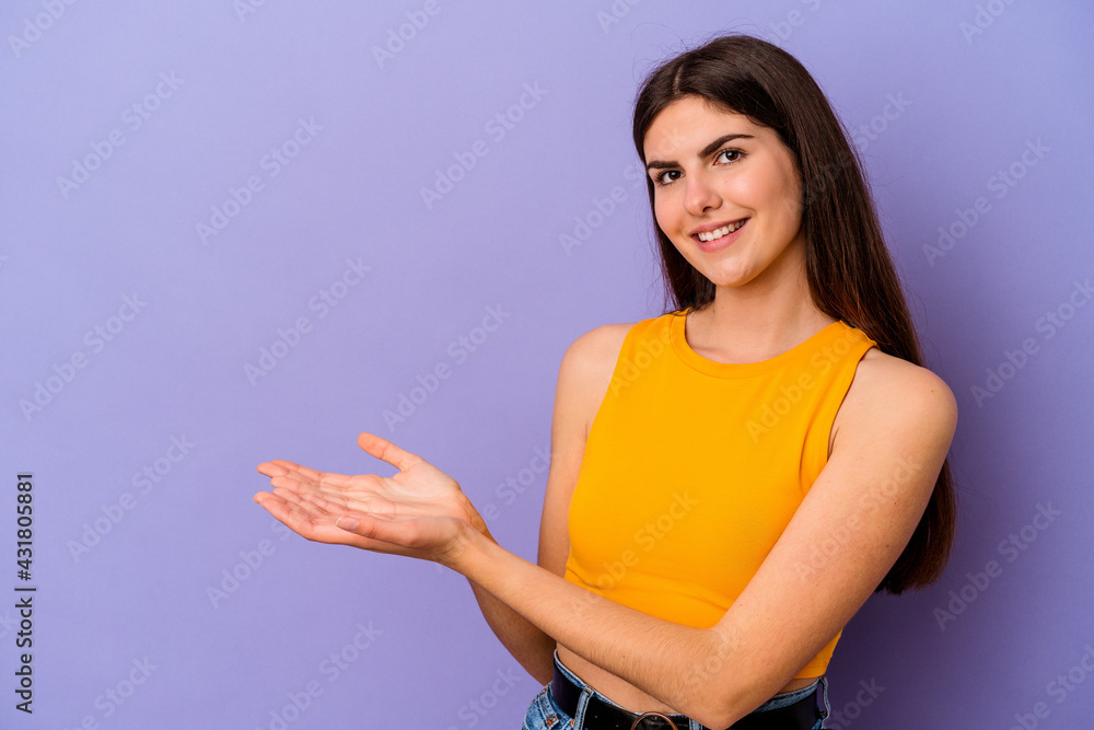 Young caucasian woman isolated on purple background holding a copy space on a palm. Young caucasian woman isolated on purple background holding a copy space on a palm.