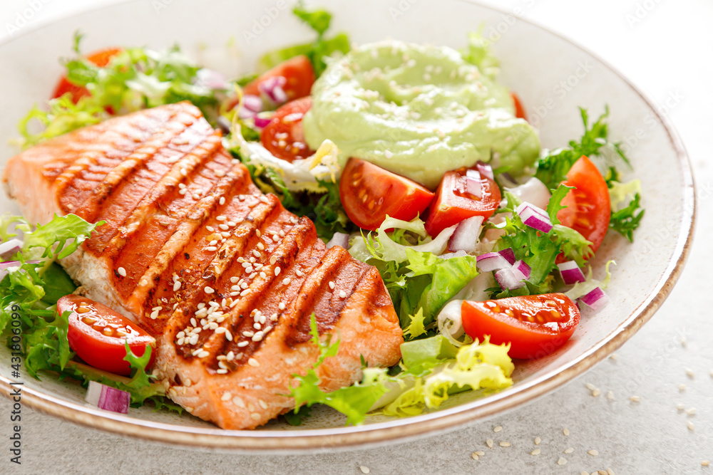 Grilled salmon fish fillet and fresh green lettuce vegetable tomato salad with avocado guacamole Grilled salmon fish fillet and fresh green lettuce vegetable tomato salad with avocado guacamole
