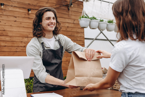 Young man as a cashier or seller at the cash register in the flower shop.