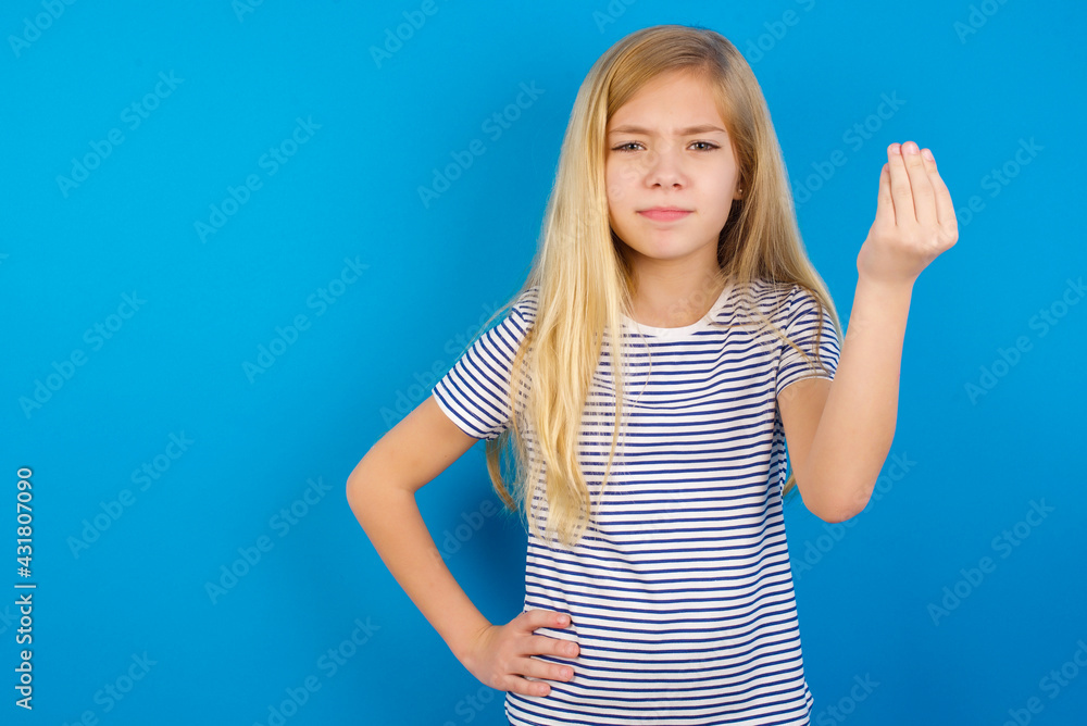 Fototapeta premium Caucasian kid girl wearing striped shirt ​against blue wall angry gesturing typical italian gesture with hand, looking to camera