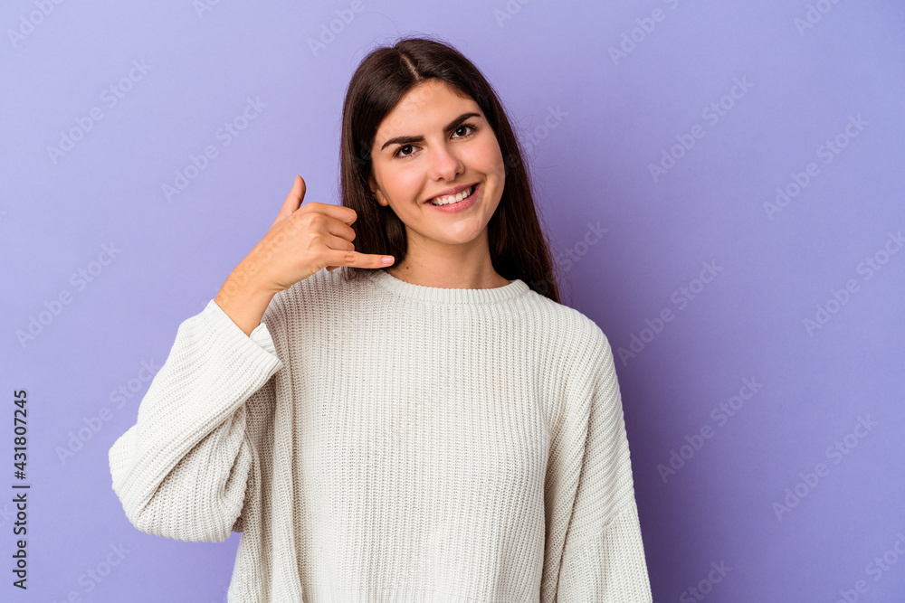 Obraz premium Young caucasian woman isolated on purple background showing a mobile phone call gesture with fingers.