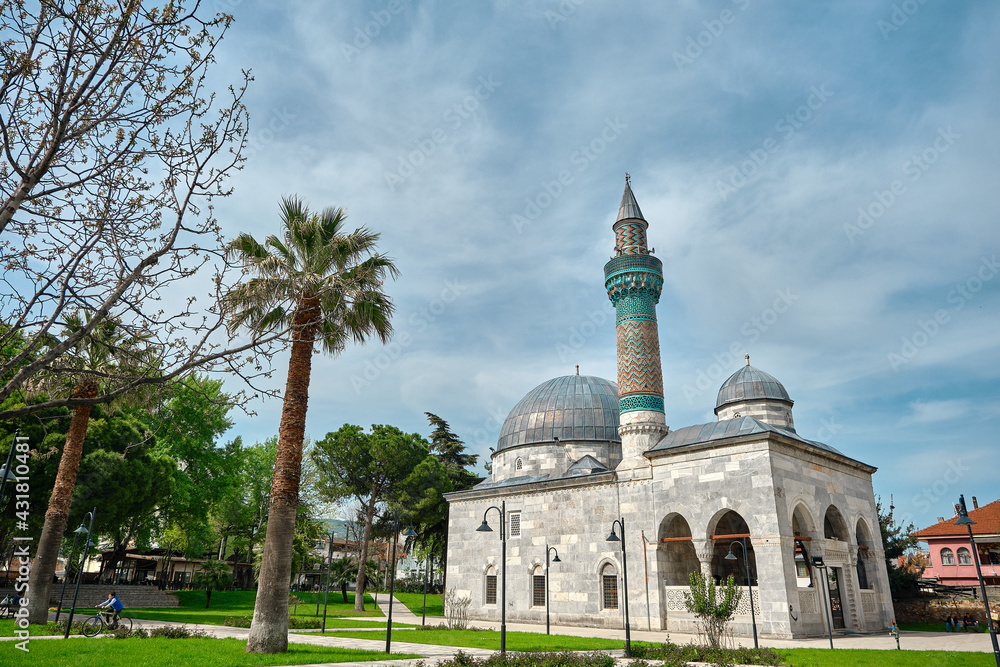 29.4.2021. Bursa, Turkey. Green mosque (yesil camii) in Nicaea (iznik) during spring and sunny day in center of the city covered by many green plants, and palm trees and it turquoise color minaret