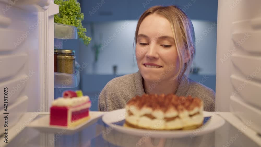 Sweet tooth woman in bathrobe at midnight opening refrigerator and cant stop eating sweet desserts. Unhealthy lifestyle Sweet tooth woman in bathrobe at midnight opening refrigerator and cant stop eating sweet desserts. Unhealthy lifestyle