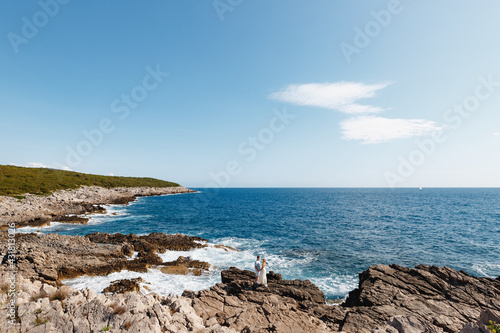 Man and woman in love stand embracing and holding hands on the rocky seashore 