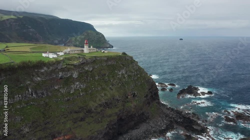 Picturesque viewpoint with Albarnaz Lighthouse (Farol de Albarnaz), Flores Island, Azores, Portugal, Europe. Drone shot of green mountains washing by atlantic ocean, 4k footage 