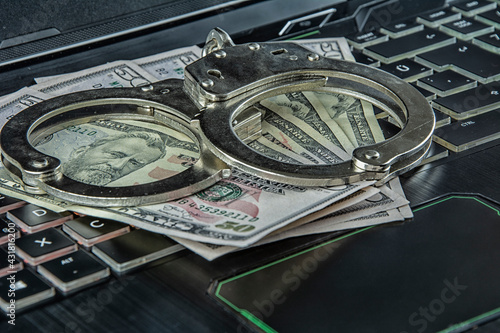 Handcuffs on dollars on the keyboard in close-up