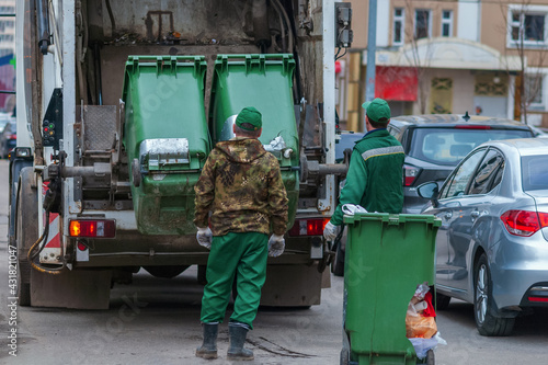 Obraz na plátně Garbage truck and workers collecting solid waste in residential area