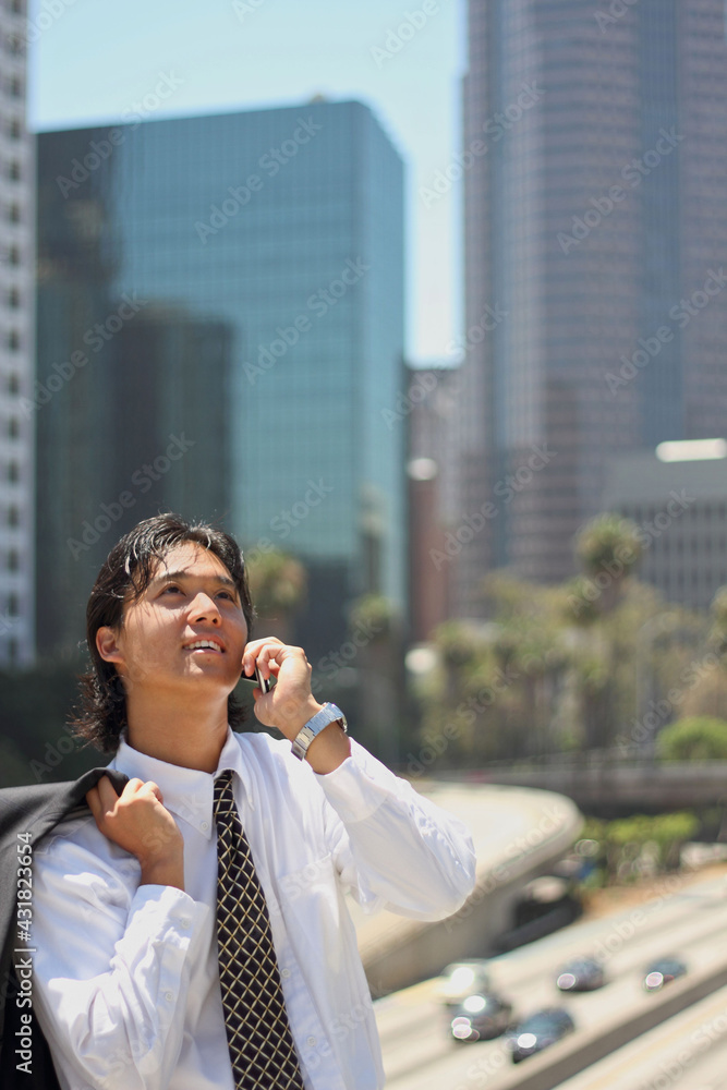 A young Japanese businessman using a mobile phone in a business district in Los Angeles, USA A young Japanese businessman using a mobile phone in a business district in Los Angeles, USA