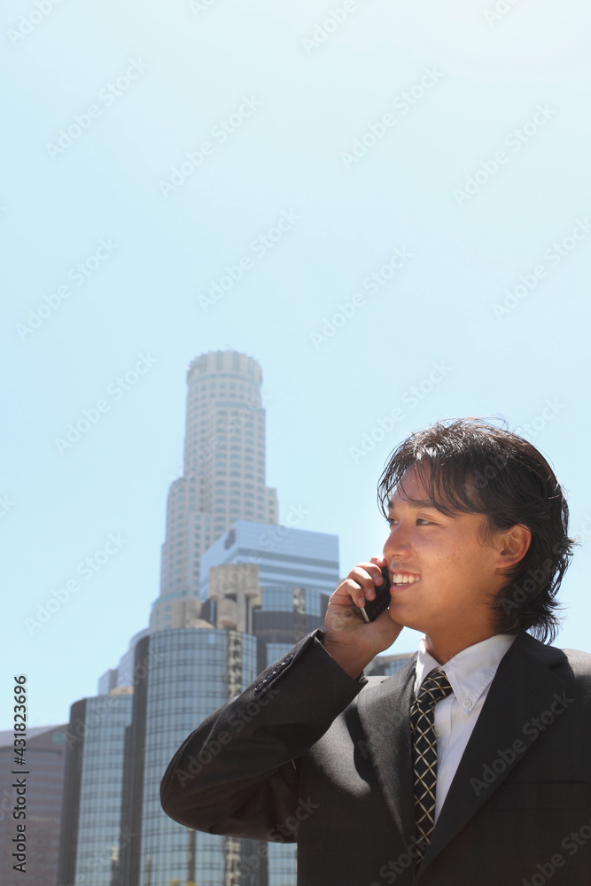 A young Japanese businessman using a mobile phone in a business district in Los Angeles, USA A young Japanese businessman using a mobile phone in a business district in Los Angeles, USA