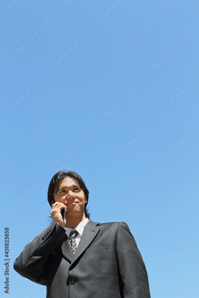 A young Japanese businessman using a mobile phone in a business district in Los Angeles, USA A young Japanese businessman using a mobile phone in a business district in Los Angeles, USA