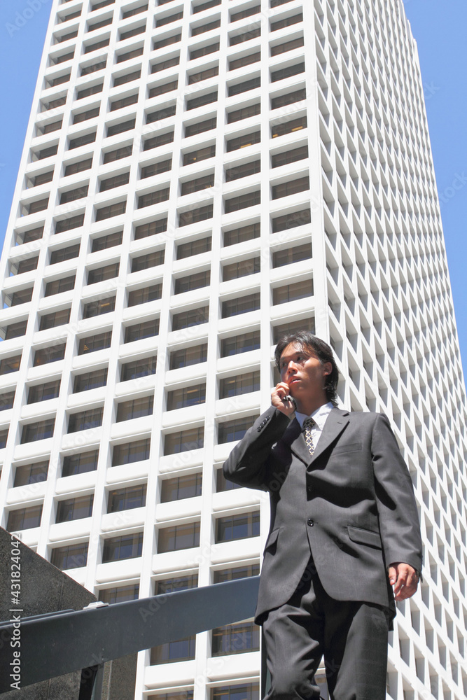 A young Japanese businessman using a mobile phone in a business district in Los Angeles, USA A young Japanese businessman using a mobile phone in a business district in Los Angeles, USA