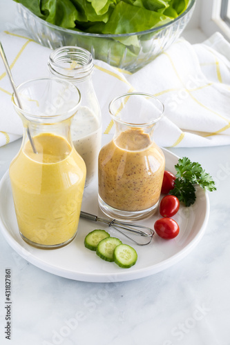 Three homemade salad dressing including turmeric tahini, honey mustard and poppyseed, taken from above.