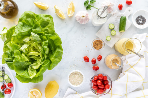 Top down view of a head of butter lettuce leaves surrounded by homemade salad dressing and other ingredients. photo