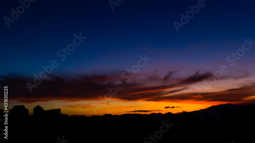 Sunset with clouds and urban silhouettes and mountains