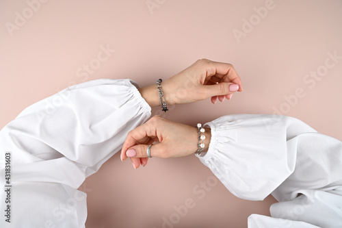 Top view of tender female hands with stylish silver bracelets on pink background.