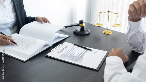 law,libra scale and hammer on the table, 2 lawyers are discussing about contract paper, law matters determination