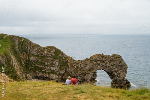 Jurassic Coast in Britain and young couple sitting on hill