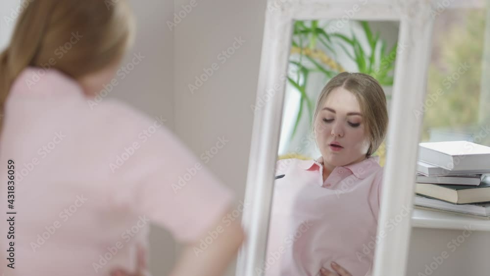 Reflection in mirror of confident chubby Caucasian woman. Portrait of self-assured young overweight lady at home in the morning. Lifestyle and femininity concept Reflection in mirror of confident chubby Caucasian woman. Portrait of self-assured young overweight lady at home in the morning. Lifestyle and femininity concept