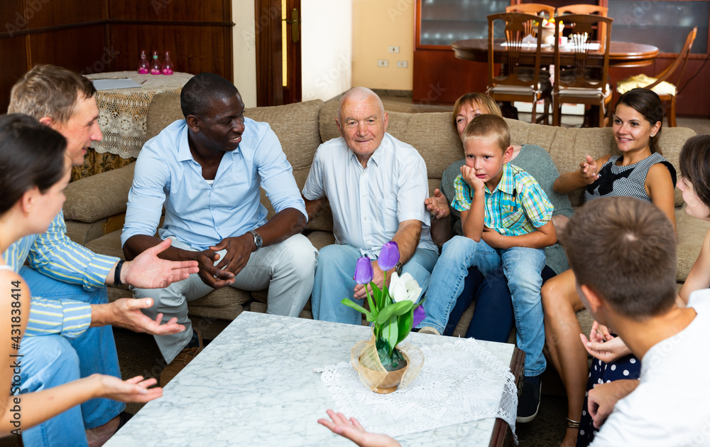 Obraz premium Big international family gathered together in parental home, cheerfully talking in living room