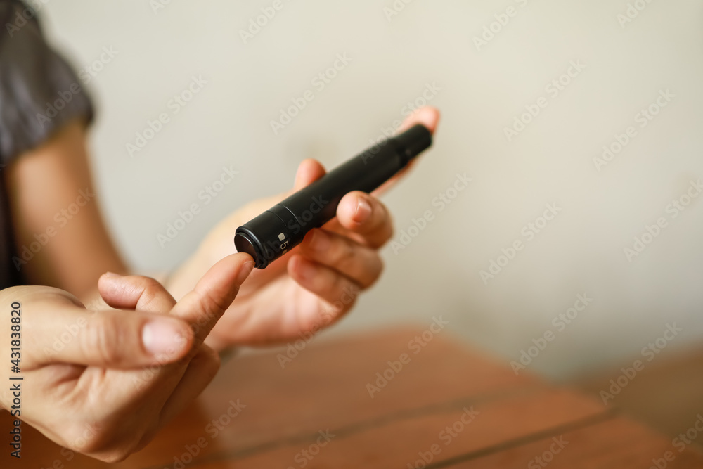 Close up of woman hands using lancet on finger to check blood sugar level by Glucose meter. Use as Medicine, diabetes, glycemia, health care and people concept. Close up of woman hands using lancet on finger to check blood sugar level by Glucose meter. Use as Medicine, diabetes, glycemia, health care and people concept.