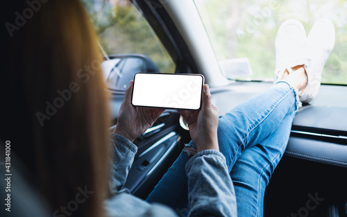 Mockup image of a woman holding and using mobile phone with blank screen in the car