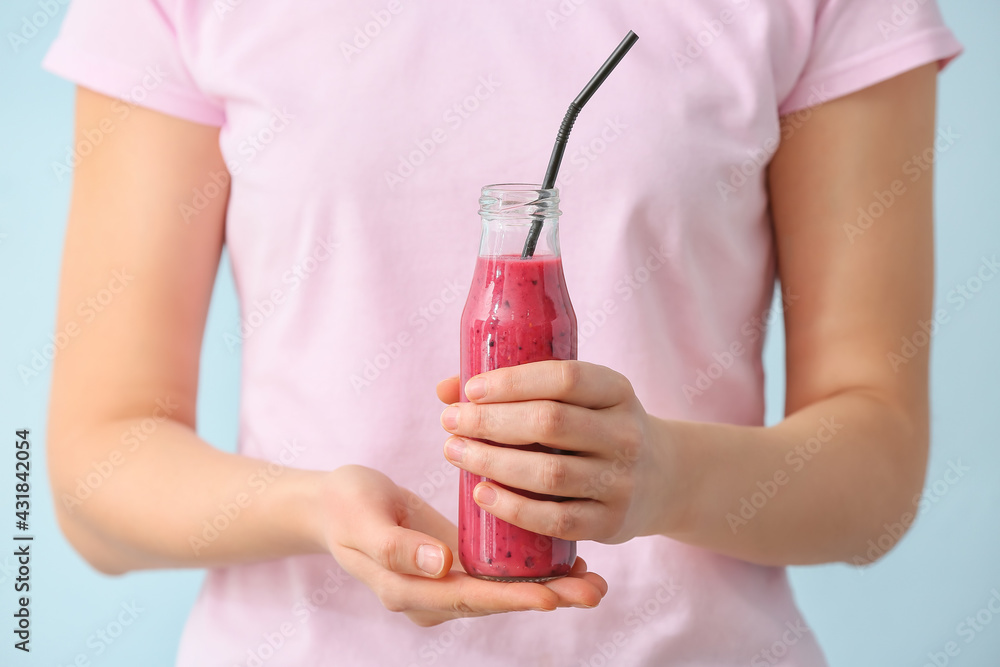 Woman with bottle of fruit smoothie on color background - obrazy, fototapety, plakaty 