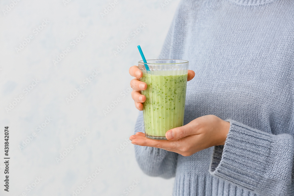 Woman with glass of fruit smoothie on light background - obrazy, fototapety, plakaty 