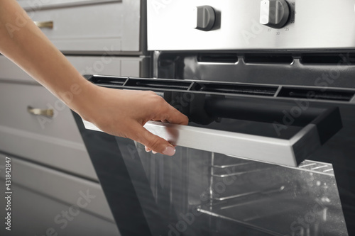 Woman opening oven in kitchen