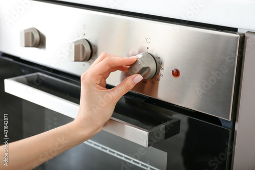 Woman adjusting oven in kitchen