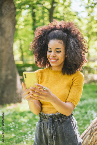 Pretty and happy afro woman typing on mobile.