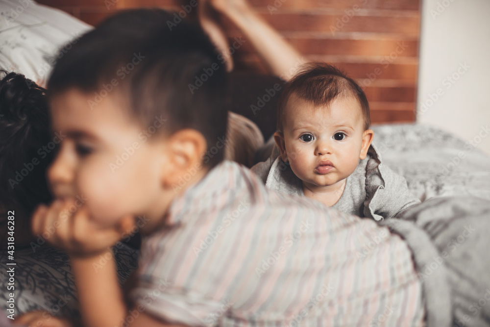 Caucasian family lying on the couch spending time together while newborn baby is looking at camera Caucasian family lying on the couch spending time together while newborn baby is looking at camera
