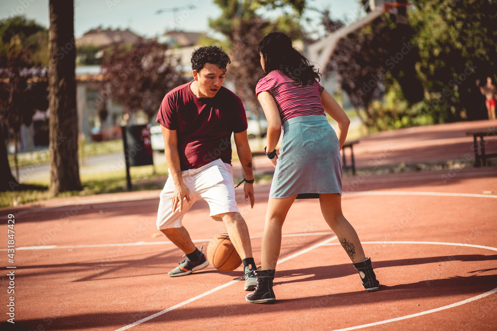 Fototapeta premium Young couple playing basketball on street court.