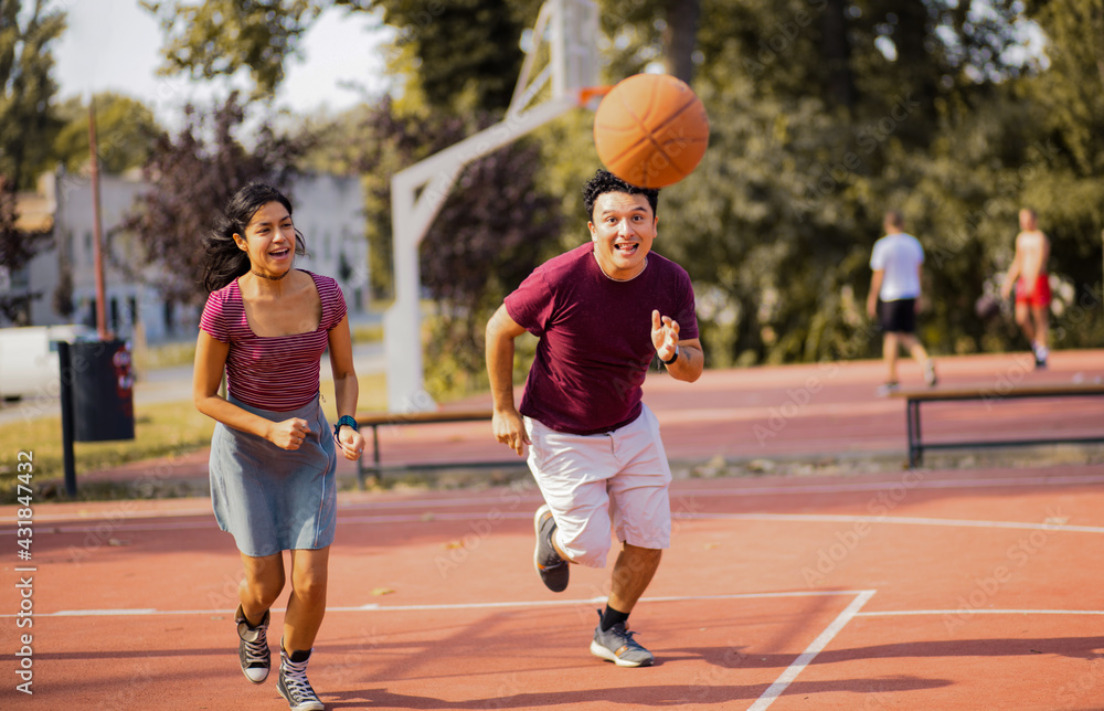 Young couple playing basketball on street court.