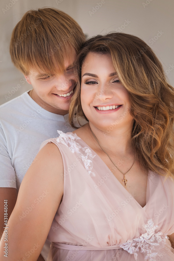 Young pretty pregnant woman hugging and smiling with handsome husband in studio Young pretty pregnant woman hugging and smiling with handsome husband in studio