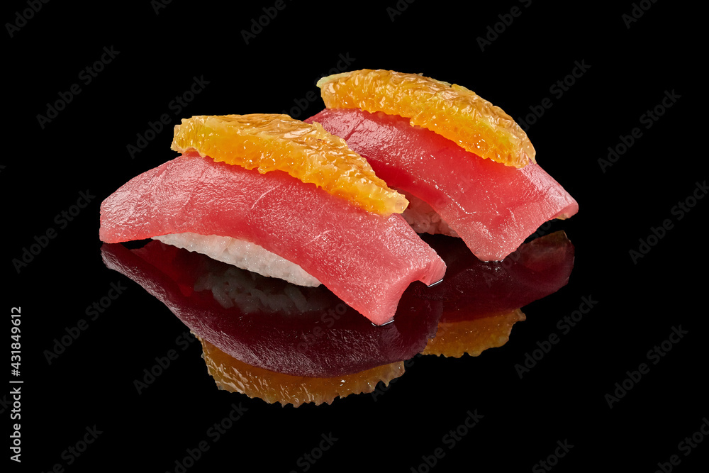 Two nigirizushi with tuna and orange on black background