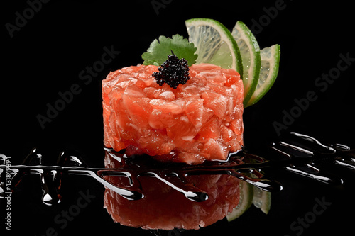 Φωτογραφία Salmon tartare with caviar, lime, soy sauce on black background