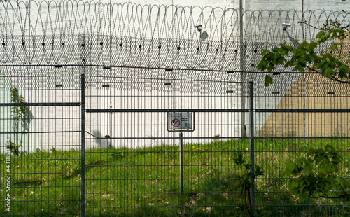 Weitwinkelaufnahme vom Schild mit der Aufschrift Kontaktaufnahme verboten auf dem Gelände der Untersuchungshaftanstalt Hamburg mit Stacheldrahtzaun im Vordergrund, Deutschland photo