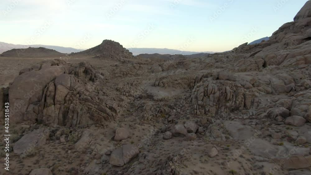Aerial Shot Of Popular Alabama Hills And Mountains At Sunset, Drone Flying Forward Over Rocky Landscape With Dirt Road Against Sky - Sierra, California